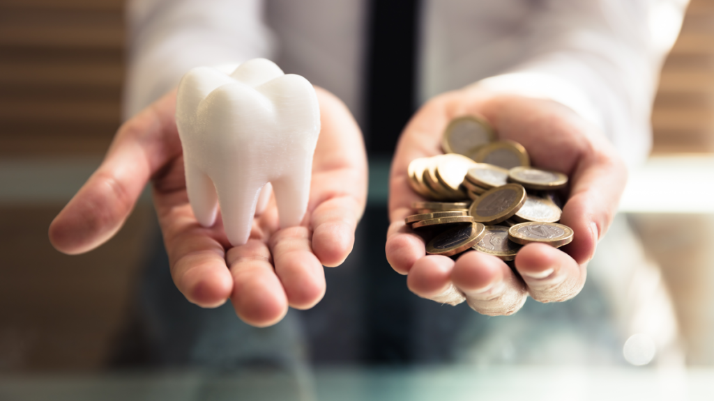 Close-up of a person's hand holding white tooth and coins