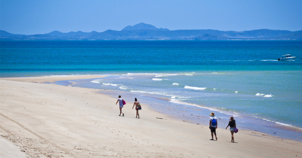 Two couples walk on an ideal beach on Keppel Island, Queensland, Australia.