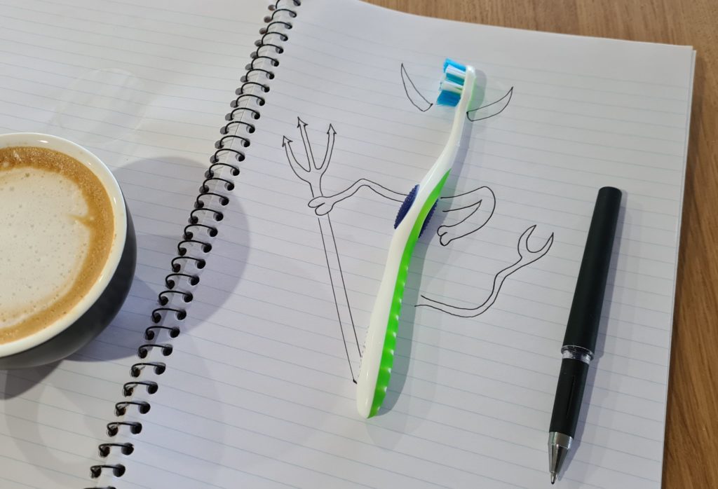 toothbrush set on a piece of notebook paper with an illustration of a creature around it