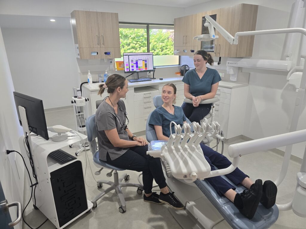 three dental professionals in a dentists office preparing for a tooth extraction procedure