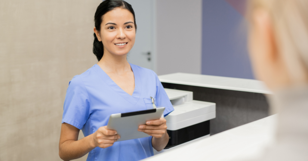 Assistant with digital tablet standing by reception counter while registering new patients.