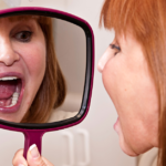 Woman at dentist office looking at her new dental implants.