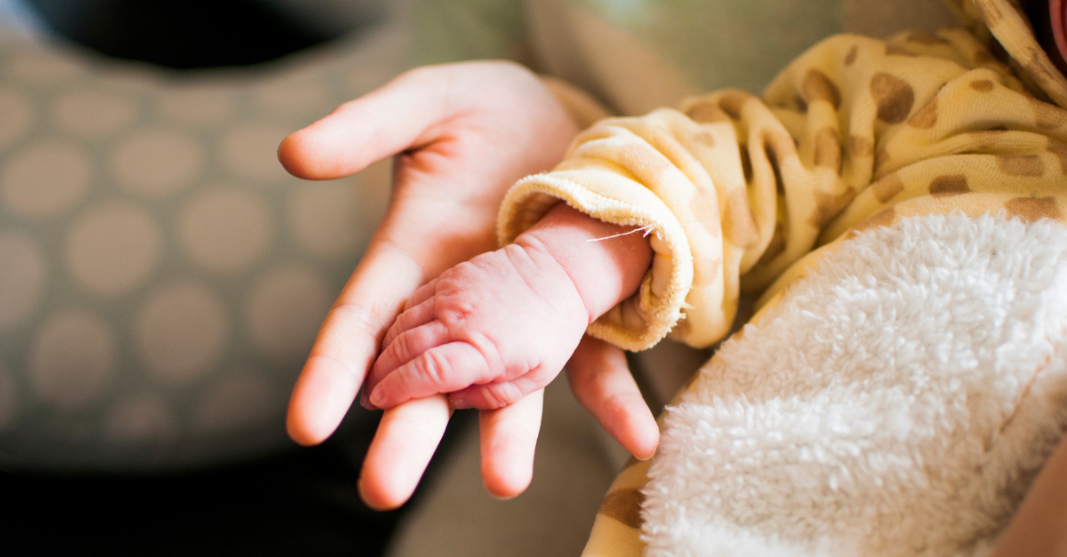 A baby's hand holding a baby's finger.