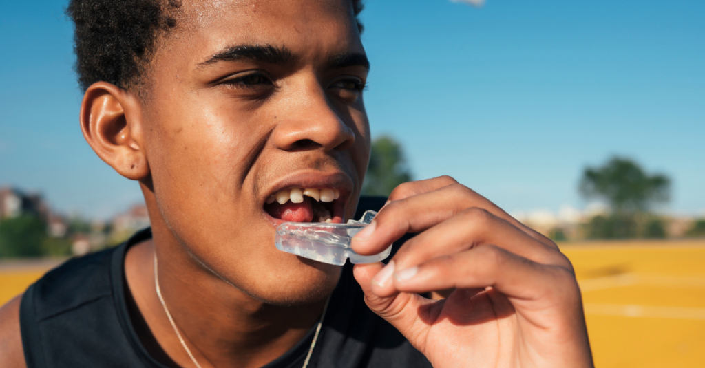 Serious black young man holding mouthguard.