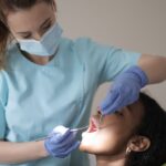 oral health therapist using dental tools to look into a patient's mouth