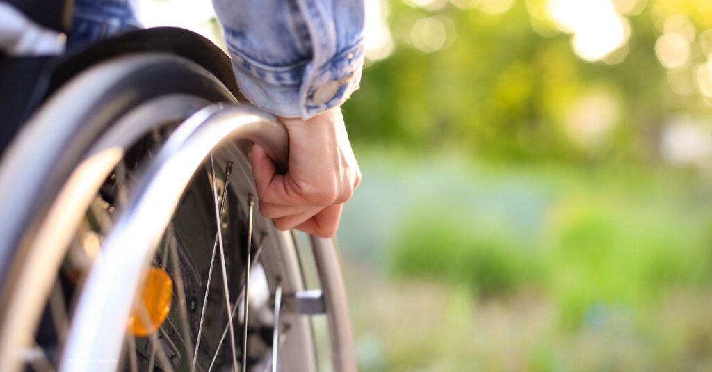 up close image of a person's hand on their wheel chair wheel