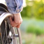 up close image of a person's hand on their wheel chair wheel