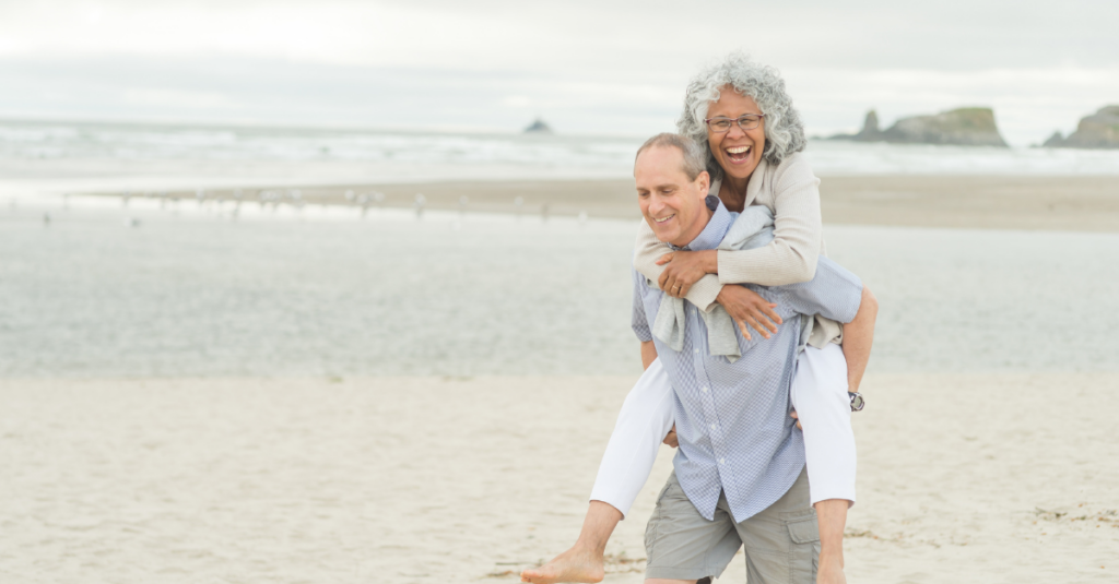 A cute mature couple enjoy each other's company as they walk along the beach.