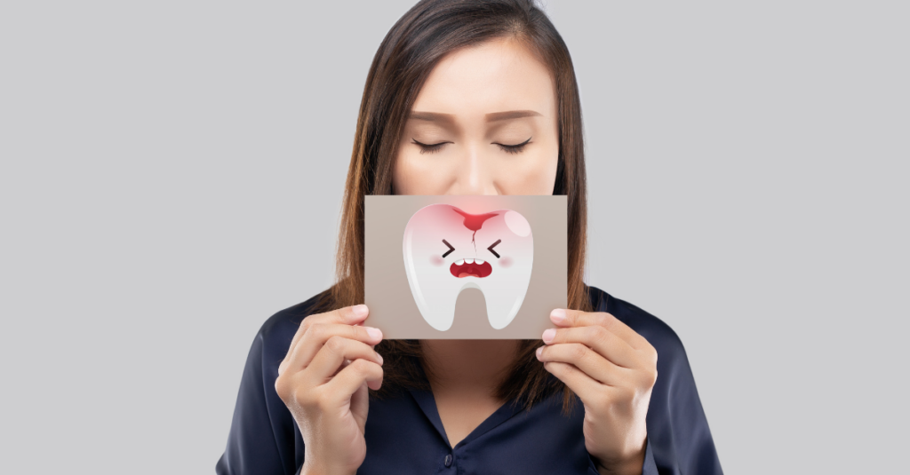 Woman holding a brown paper with a broken tooth cartoon picture of his mouth.