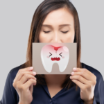 Woman holding a brown paper with a broken tooth cartoon picture of his mouth.