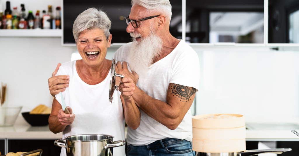 Happy senior couple having fun cooking at home.