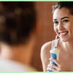 person looking into a mirror holding a water flosser