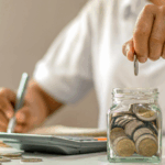 Close-up of a woman putting coins in a jar.
