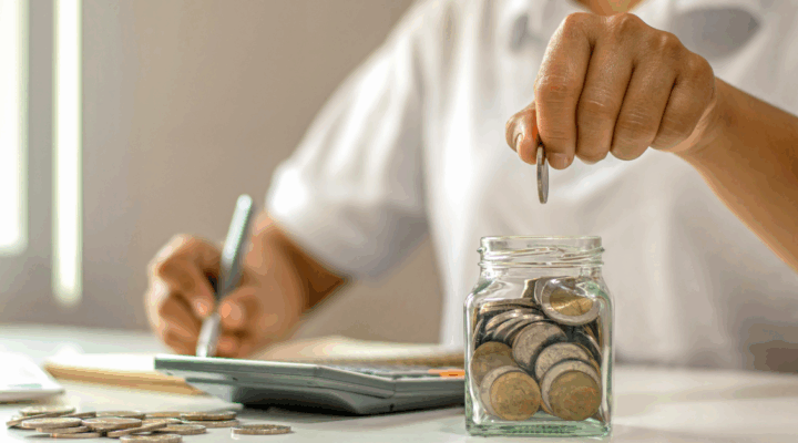 Close-up of a woman putting coins in a jar.